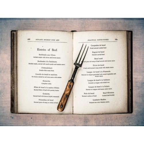 Old cookery book open with an old fork spoon