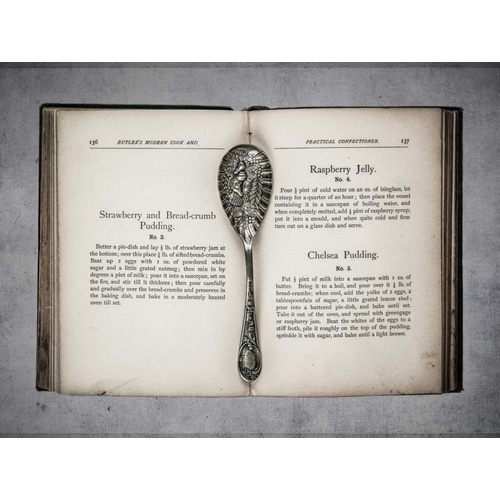 Old cookery book open with an old jam spoon