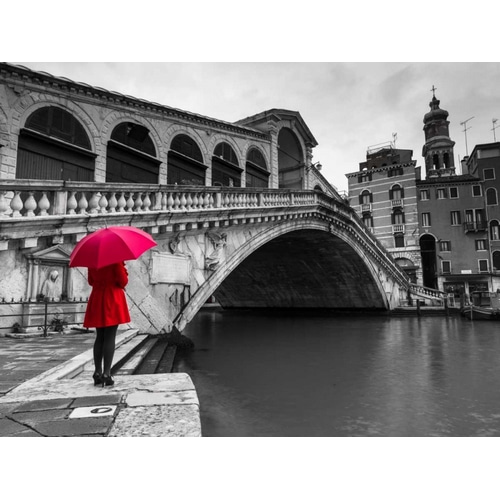 A woman in a red dress holding red umbrella and standing next to the Rialto bridge, Venice, Italy