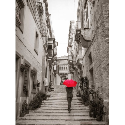 Tourist with umbrella in steps through houses in Birgu, Malta