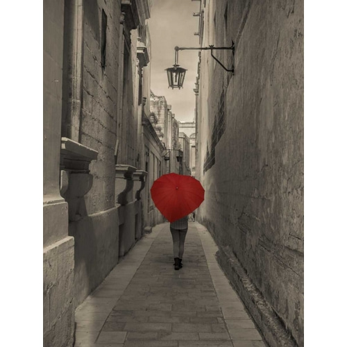 Tourist with heart shaped umbrella walking through narrow street of Mdina, Malta