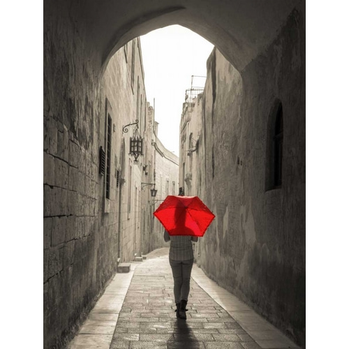 Tourist with umbrella walking through narrow street in Mdina, Malta