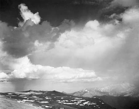 Mountain tops, low horizon, dramatic clouded sky, in Rocky Mountain National Park, Colorado, ca. 194