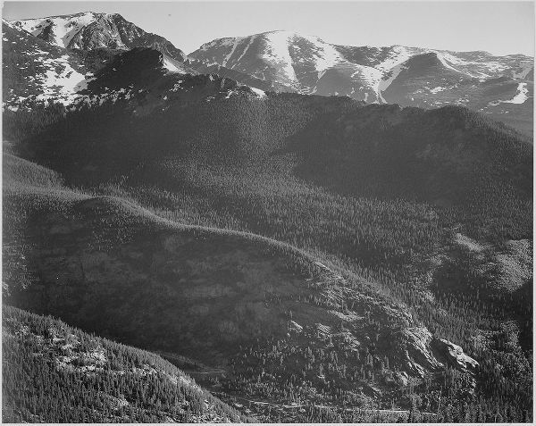 View of wooded hills with mountains in background, in Rocky Mountain National Park, Colorado, ca. 19
