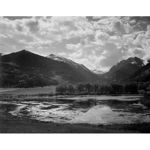 Lake and trees in foreground, mountains and clouds in background, in Rocky Mountain National Park, C