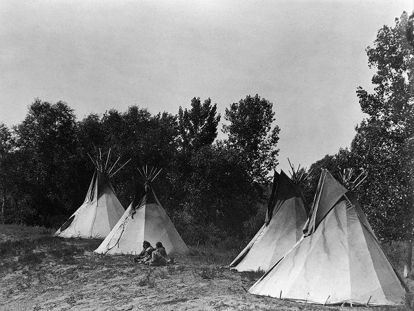 An Assiniboin camp containing four tepees with Indians seated on ground